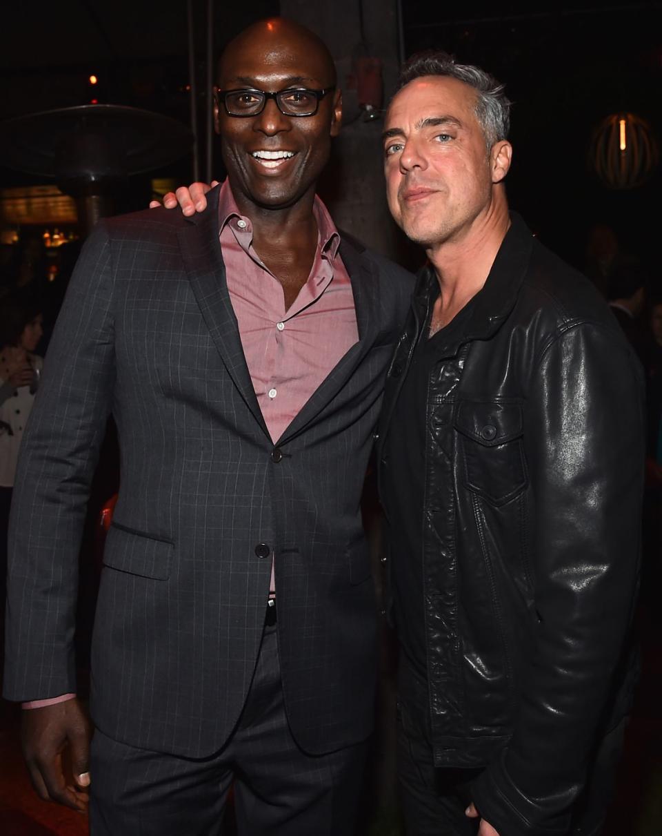 lance reddick, wearing a black suit, and titus welliver, wearing a black leather jacket