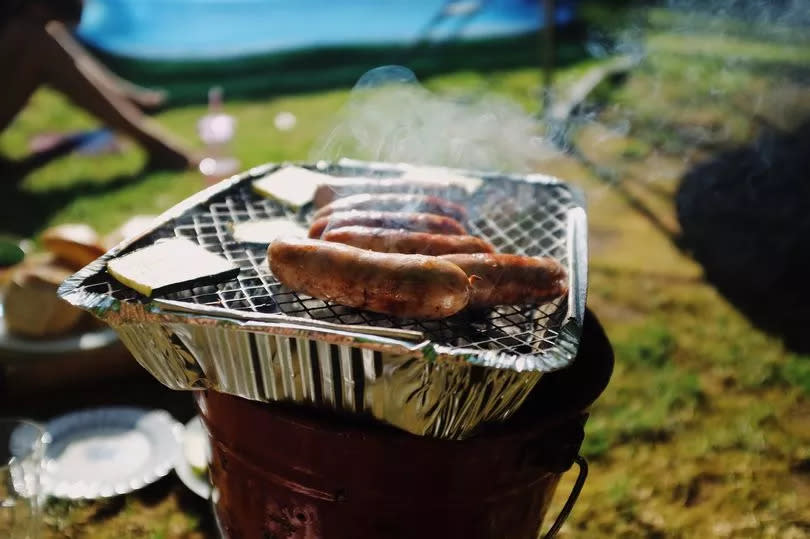 Disposable BBQ with sausages in sunny back garden