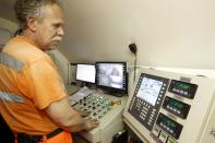 An employee looks at monitors to control the mixture of concrete on the special train 'Helvetia' in the NEAT Gotthard Base tunnel near Erstfeld May 7, 2012. The train, which is 481 metres (1578 ft) long and weighs 787 tons, is constructed to produce concrete for the installation of the railway tracks in the tunnel. Crossing the Alps, the world's longest train tunnel should become operational at the end of 2016. The project consists of two parallel single track tunnels, each of a length of 57 km