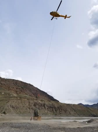 A helicopter delivers equipment for a trench to be used as a holding pond for migrating salmon near the Big Bar landslide