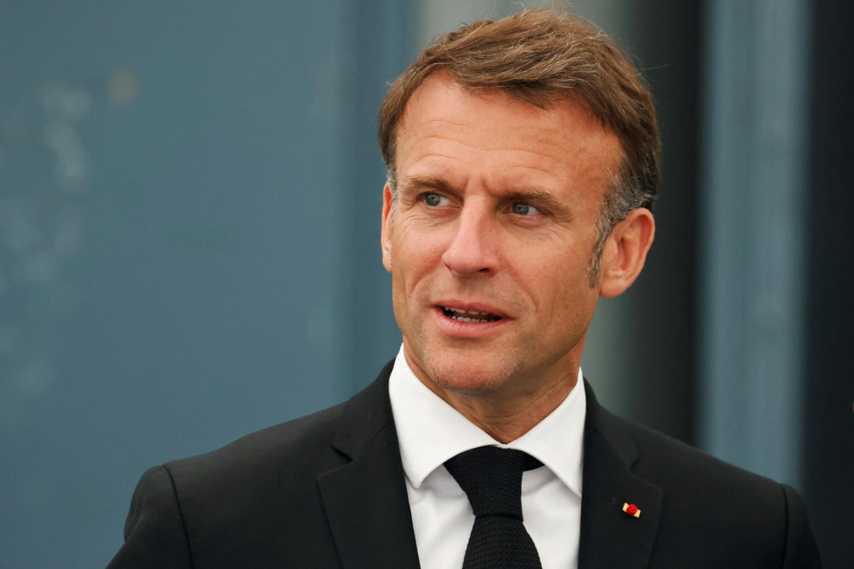 French President Emmanuel Macron, wearing a black suit and black tie, at a solemn anniversary ceremony. 