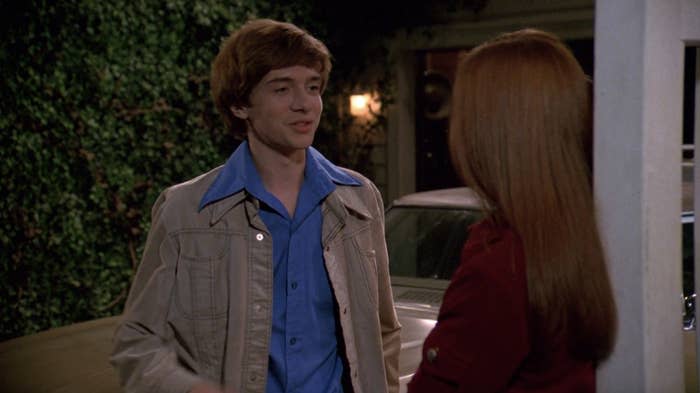 Eric looks at Donna, leaning against the railing of his patio