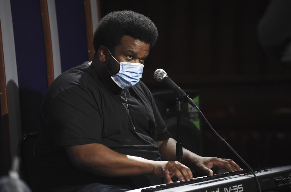 In this April 20, 2020, photo, comedian Craig Robinson wears a mask as he plays the keyboard during a "Laughter is Healing" stand-up comedy livestream event at the Laugh Factory comedy club, Monday, April 20, 2020, in Los Angeles. With comedy clubs closed and concert tours put on hold, comics like Robinson, Tiffany Haddish, Will C and others are keeping the jokes flowing on webcasts and Zoom calls even without the promise of a payday, because they say the laughs are needed now more than ever. (AP Photo/Chris Pizzello)