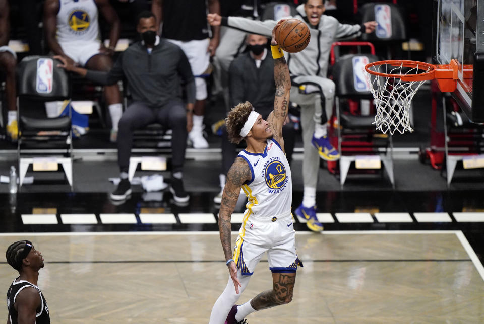 Brooklyn Nets guard Caris LeVert (22) watches, far left, as Golden State Warriors forward Kelly Oubre Jr., (12) dunks the ball during the first quarter of an opening night NBA basketball game, Tuesday, Dec. 22, 2020, in New York. (AP Photo/Kathy Willens)