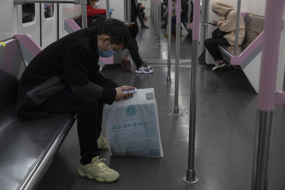 In this April 1, 2020, photo, a passenger takes the subway in Wuhan in central China's Hubei province. Life in China post-coronavirus outbreak is ruled by a green symbol on a smartphone screen. Green signifies the "health code" that says the user is symptom-free. It is required to board a subway, check into a hotel or enter Wuhan, the city where the global pandemic began. (AP Photo/Ng Han Guan)