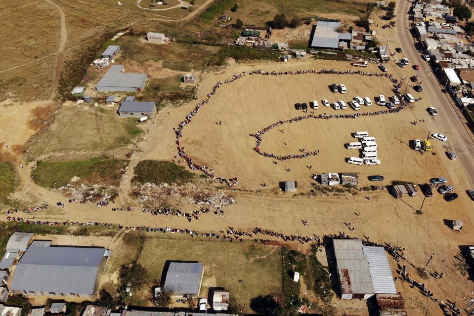 FILE — In this May 2, 2020 file photo thousands line up to receive food handouts in the Olievenhoutbos township of Midrand, South Africa. (AP Photo/Jerome Delay, File)