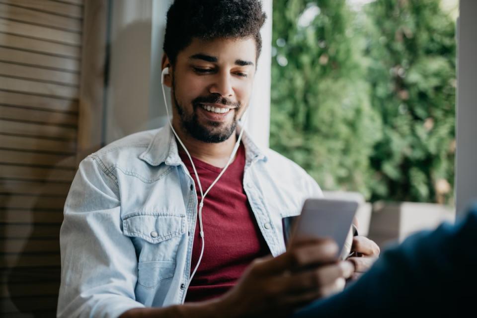 A man looking at a smartphone and listening to headphones.