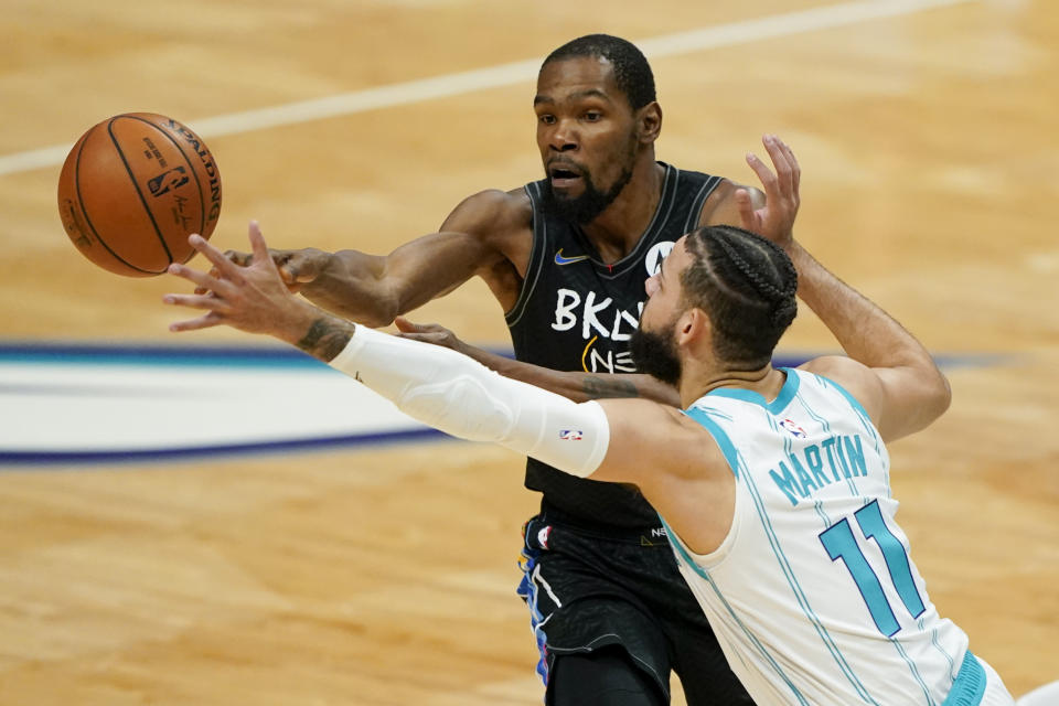 Brooklyn Nets forward Kevin Durant passes around Charlotte Hornets forward Cody Martin during the first half of an NBA basketball game in Charlotte, N.C., Sunday, Dec. 27, 2020. (AP Photo/Chris Carlson)