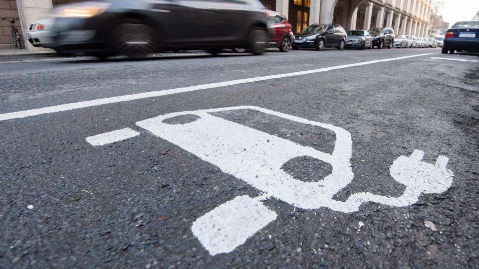 Ein Symbol für ein Elektroauto markiert einen Parkplatz neben einer E-Ladesäule.