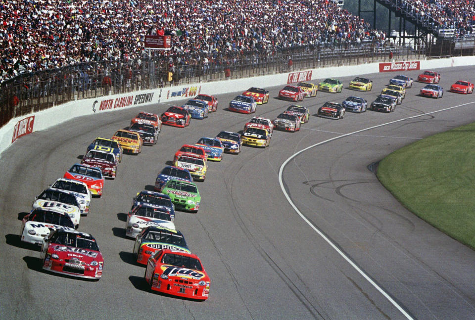 FILE - Ricky Rudd, front right, and Jeff Burton, front left, lead the field as they take the green flag to start the NASCAR Cup Series auto race at North Carolina Motor Speedway near Rockingham, N.C., Feb. 21, 1999. The track, now owned by Rockingham Properties LLC, completed repaving in December in hopes of luring NASCAR back, along with the CARS Tour, ARCA and Formula Drift. The track currently seats 25,000 spectators, and SAFER barriers have already been added to the track. (AP Photo/Chuck Burton, File)