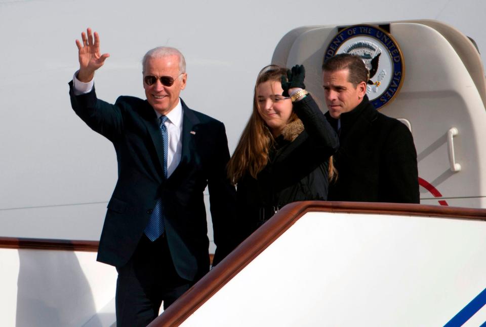 In this file photo taken Dec. 3, 2013, then-Vice President Joe Biden waves as he walks out of Air Force Two with his granddaughter, Finnegan Biden and son Hunter Biden upon their arrival in Beijing.