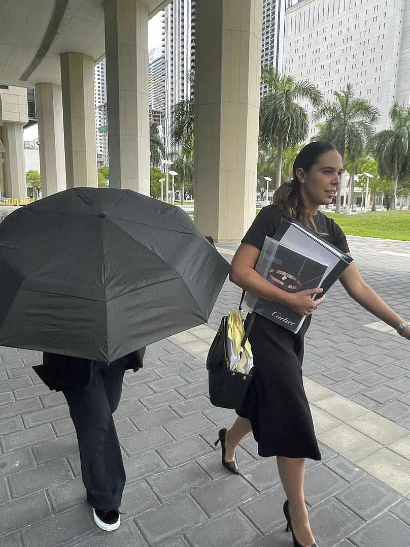 Celebrity handbag designer Nancy Gonzalez hides under an umbrella as she walks with her lawyer Andrea Lopez outside the federal courthouse Monday, April 22, 2024, in Miami.