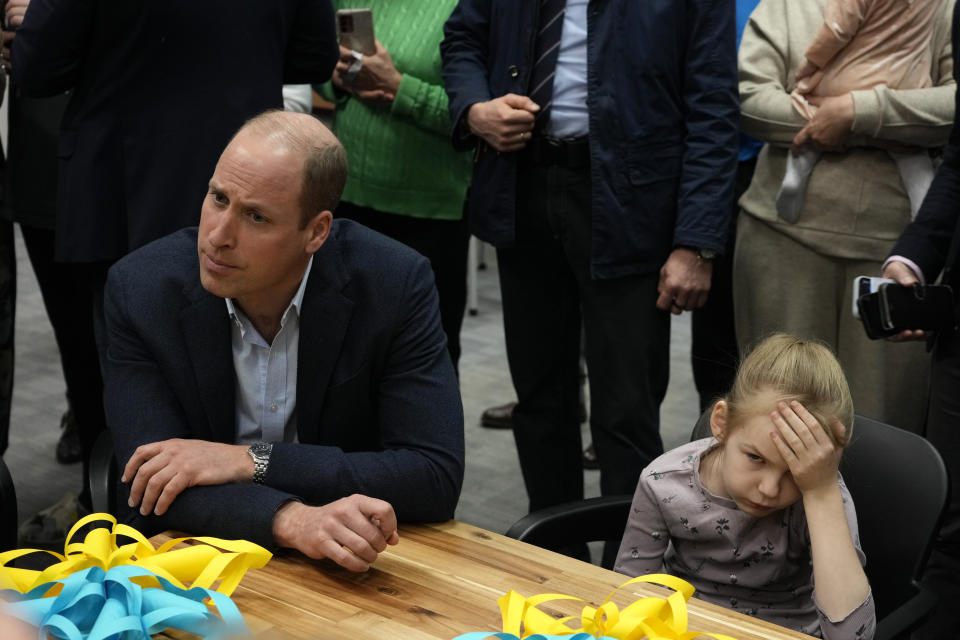 Young girl holds her head as Britain's Prince William visits an accommodation centre, for Ukrainians who fled the war, in Warsaw, Poland, Wednesday, March 22, 2023. (AP Photo/Czarek Sokolowski)