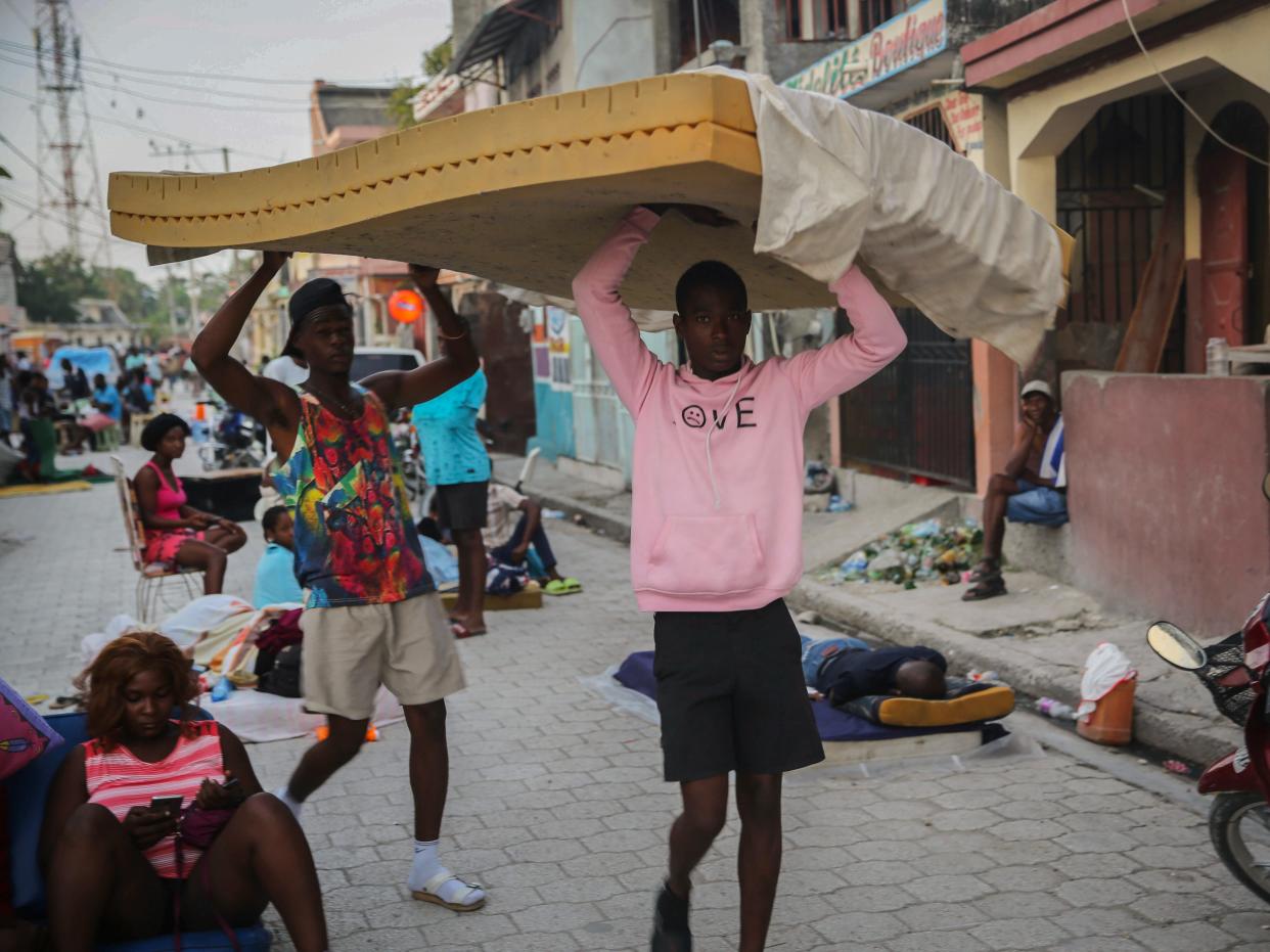 Men carry a mattress as people sleep on the streets after Saturday’s 7.2 magnitude earthquake in Les Cayes, Haiti, Sunday, Aug. 15, 2021 (AP)