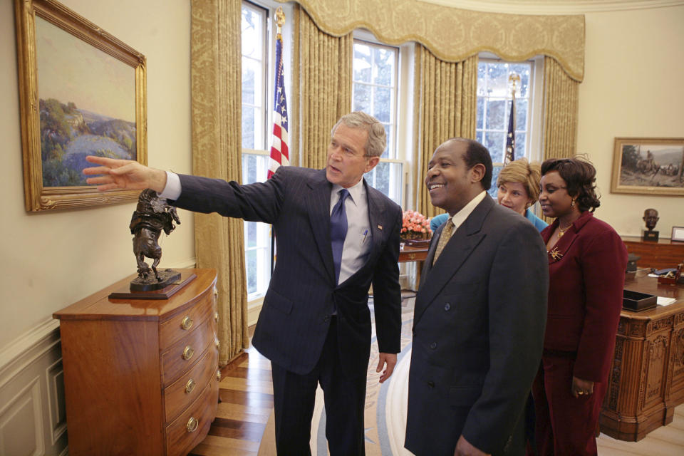 FILE - In this Thursday, Feb. 17, 2005 file photo provided by the White House, President Bush, left, and first lady Laura Bush, 2nd right, meet with Paul Rusesabagina, center-right, and his wife, Tatiana, right, in the Oval Office. Paul Rusesabagina, who was portrayed in the film "Hotel Rwanda" as a hero who saved the lives of more than 1,200 people from the country's 1994 genocide, and is a well-known critic of President Paul Kagame, has been arrested by the Rwandan government on terror charges, police announced on Monday, Aug. 31, 2020.(Eric Draper/The White House via AP )