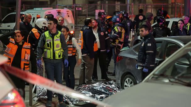 PHOTO: Israeli emergency service personnel and security forces stand near a covered body at the site of a reported attack in a settler neighborhood of Israeli-annexed east Jerusalem, on Jan. 27, 2023. (Ahmad Gharabli/AFP via Getty Images)