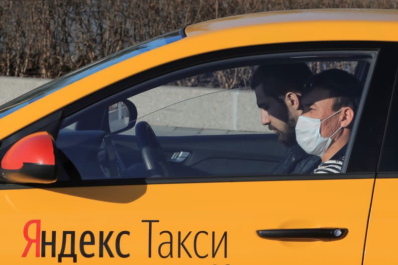 A taxi driver with a protective mask sits inside a car in Moscow