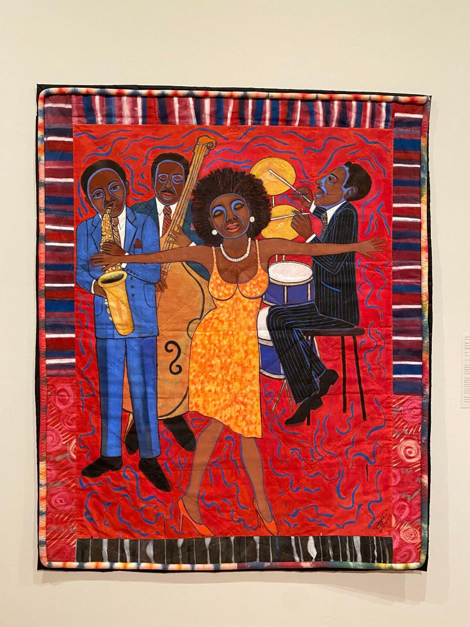 Faith Ringgold's "Jazz Stories: Mama Can Sing, Papa Can Blow #1: Somebody Stole My Broken Heart," quilt is crafted from acrylic on canvas with a pieced fabric border.