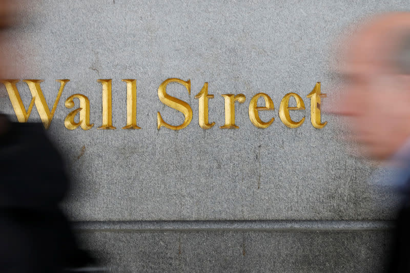 People walk by a Wall Street sign close to the New York Stock Exchange (NYSE) in New York, U.S., April 2, 2018. REUTERS/Shannon Stapleton/Files