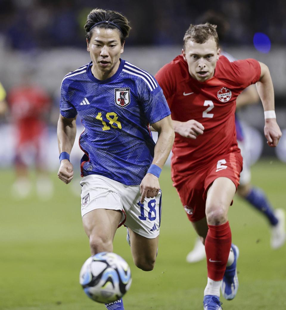 Takuma Asano, left, of Japan, is chased by Alistair Johnston of Canada during a friendly soccer match in Niigata, northern Japan, Friday, Oct. 13, 2023. (Kyodo News via AP)