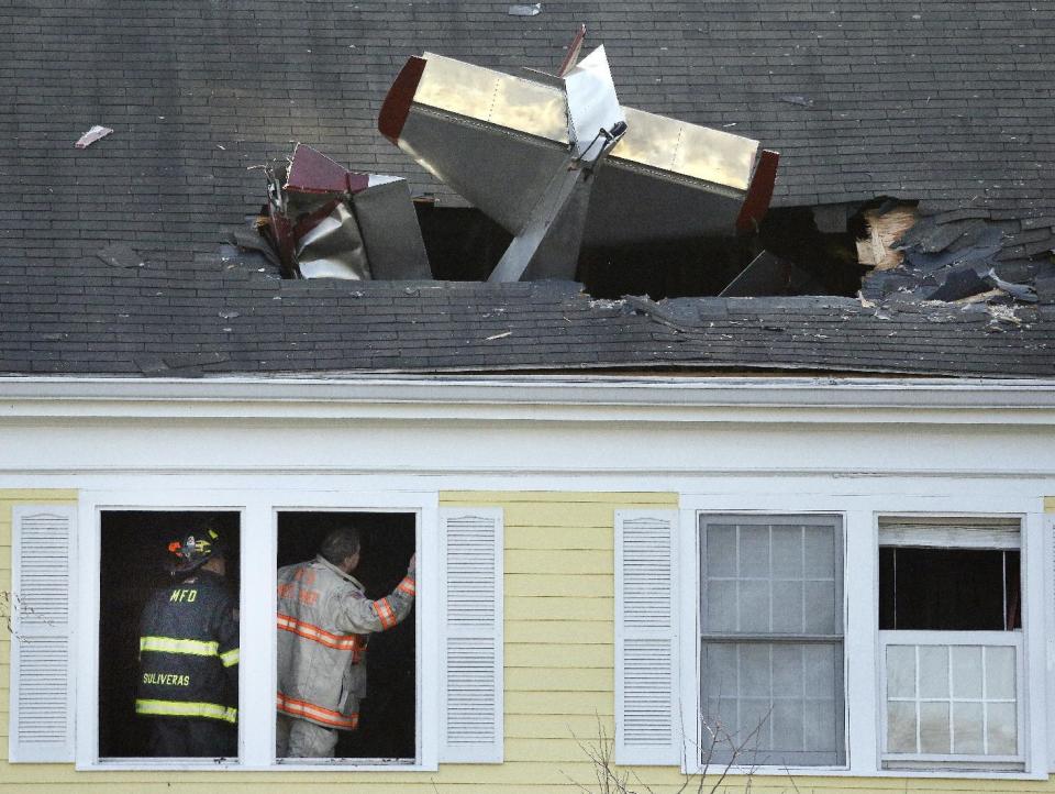 Firefighters investigate the scene after a single-engine aircraft crashed into a building across the Merrimack River from Lawrence Municipal Airport, Tuesday, Feb. 28, 2017, in Methuen, Mass. According to police, the pilot of the home-built plane was killed, while no one in the building was hurt. (AP Photo/Elise Amendola)