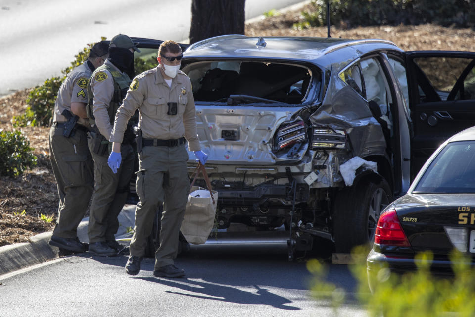 Los Angeles County Sheriff deputies gather evidence from Tiger Woods' car after a crash.