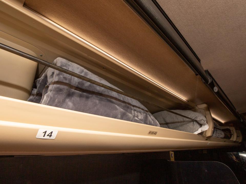 The upper storage area of the bus with a blanket.