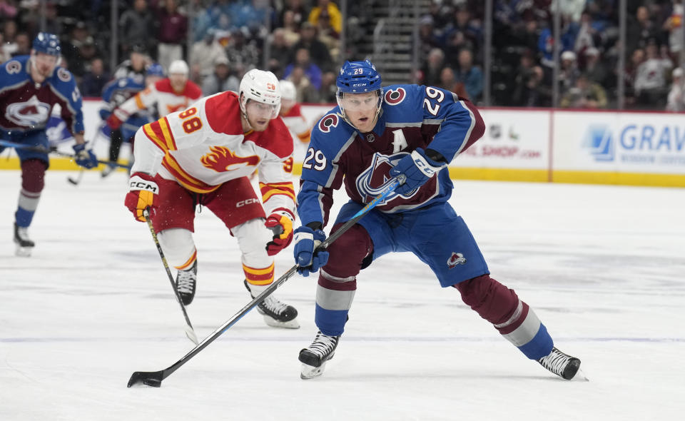 Colorado Avalanche center Nathan MacKinnon, front, drives with the puck past Calgary Flames defenseman Ilya Solovyov in the first period of an NHL hockey game, Monday, Dec. 11, 2023, in Denver. (AP Photo/David Zalubowski)