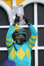 Joel Rosario holds a trophy after he rode Army Wife to win the Black-Eyed Susan Stakes horse race at Pimlico Race Course, Friday, May 14, 2021, in Baltimore. (AP Photo/Julio Cortez)