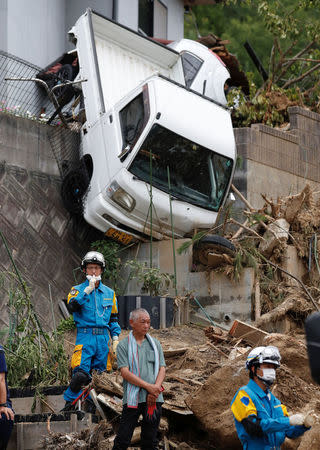 A family member of missing people watches search and rescue operations at a landslide site caused by a heavy rain in Kumano Town, Hiroshima Prefecture, western Japan, July 11, 2018. REUTERS/Issei Kato