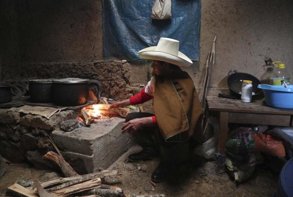 Pedro Castillo cooks breakfast for his family in his home in Chugur, Peru.