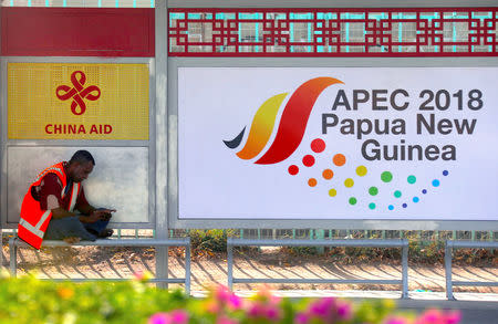 A local sits at a bus stop displaying a China Aid emblem and an Asia Pacific Economic Cooperation (APEC) banner in central Port Moresby, the capital city of the poorest nation in the 21-member APEC group, in Papua New Guinea, November 15, 2018. REUTERS/David Gray