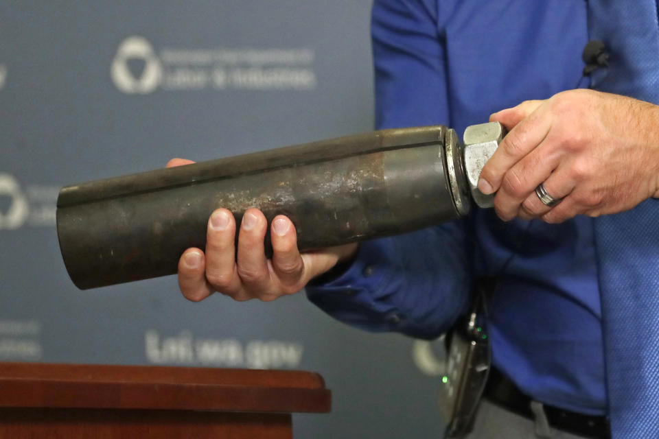 Brian Haight, Crane Program manager for Washington state's Department of Labor and Industries, holds a 26-pound pin and sleeve of the type used in the collapse of a crane earlier in the year in Seattle that killed four, Thursday, Oct. 17, 2019, in Tukwila, Wash. Washington State's L&I released the results of its investigation on the collapse Thursday. It found, as experts have long suspected, that the crane toppled because workers who were disassembling it had prematurely removed pins securing the sections of the crane's mast. (AP Photo/Elaine Thompson)