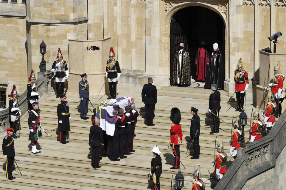 The coffin is carried up the steps at St. George's Chapel by pallbearers as other military members stand nearby.