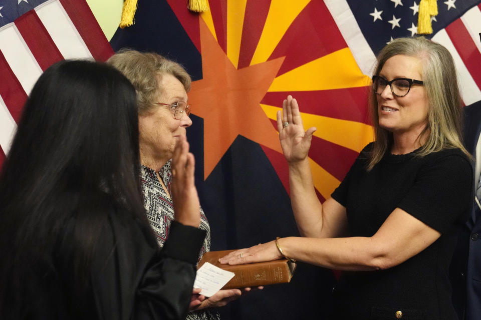 The new Arizona Democratic Gov. Katie Hobbs, right, takes the oath of office in a ceremony as U.S. Circuit Judge for the Ninth Circuit Court of Appeals Roopali Desai, left, administers the oath while Hobbs' mother Linda Hobbs holds the bible at the state Capitol in Phoenix, Monday, Jan. 2, 2023. (AP Photo/Ross D. Franklin, Pool)