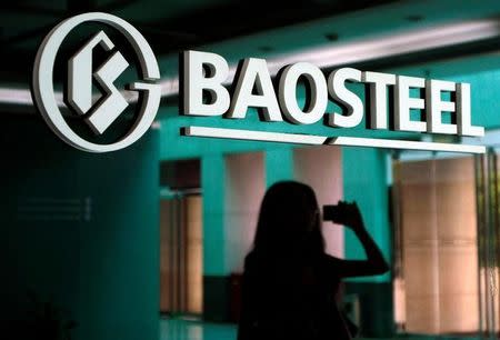 A woman is reflected on a wall with a company logo of Baosteel Group at an office in Shanghai, July 24, 2011. REUTERS/Stringer/File Photo