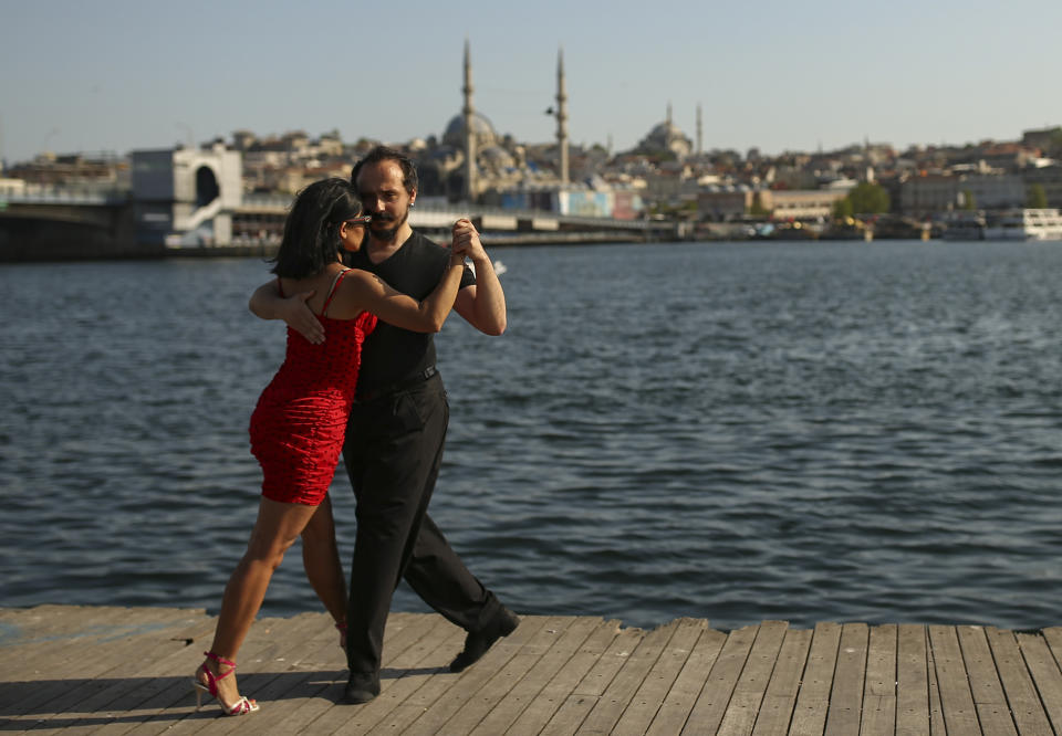 A couple dance by the Golden Horn leading to the Bosphorus Strait separating Europe and Asia, in Istanbul, Friday, May 14, 2021. Turkey is in the final days of a full coronavirus lockdown and the government has ordered people to stay home and businesses to close amid a huge surge in new daily infections. But millions of workers are exempt and so are foreign tourists. Turkey is courting international tourists during an economic downturn and needs the foreign currencies that tourism brings to help the economy as the Turkish lira continues to sink. (AP Photo/Emrah Gurel)