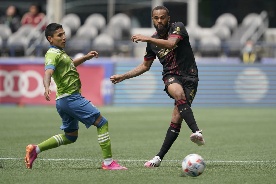 Atlanta United defender Anton Walkes, right, kicks the ball in front of Seattle Sounders forward Raul Ruidiaz, left, during the first half of an MLS soccer match, Sunday, May 23, 2021, in Seattle. (AP Photo/Ted S. Warren)