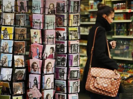 A woman passes racks of greetings cards displayed in a shop in London March 25, 2014. REUTERS/Luke MacGregor