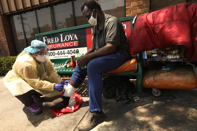 HOLLYWOOD, CA - AUGUST 18, 2020 - - Nurse Richelle Legaspi, a member of the outreach team with The Center, helps bandage a wound Pookie Moore's leg in East Hollywood on August 18,, 2020. Moore has been living homeless for the past two years. Members of the outreach team with The Center have been helping the homeless who have been dealing with the coronavirus pandemic and deliver food and water during the heat wave. The Center is a non-profit organization that has been helping the homeless community in Hollywood for many years. (Genaro Molina / Los Angeles Times)