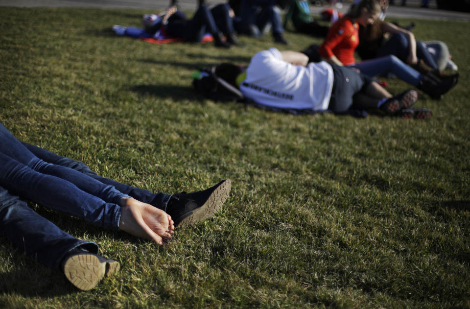 In this Wednesday, Feb. 12, 2014, photo, a couple at left, lie on the lawn under the Olympic cauldron at the 2014 Winter Olympics, in Sochi, Russia. Temperatures were near 60 degrees Fahrenheit in Sochi on Wednesday. (AP Photo/David Goldman)