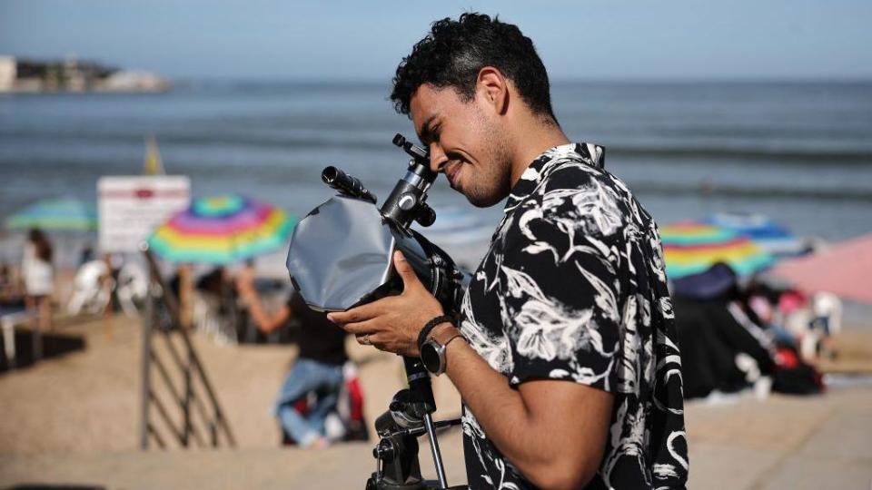 Un hombre prepara su telescopio para ver el eclipse del 8 de abril de 2024 en Mazatlán, México.