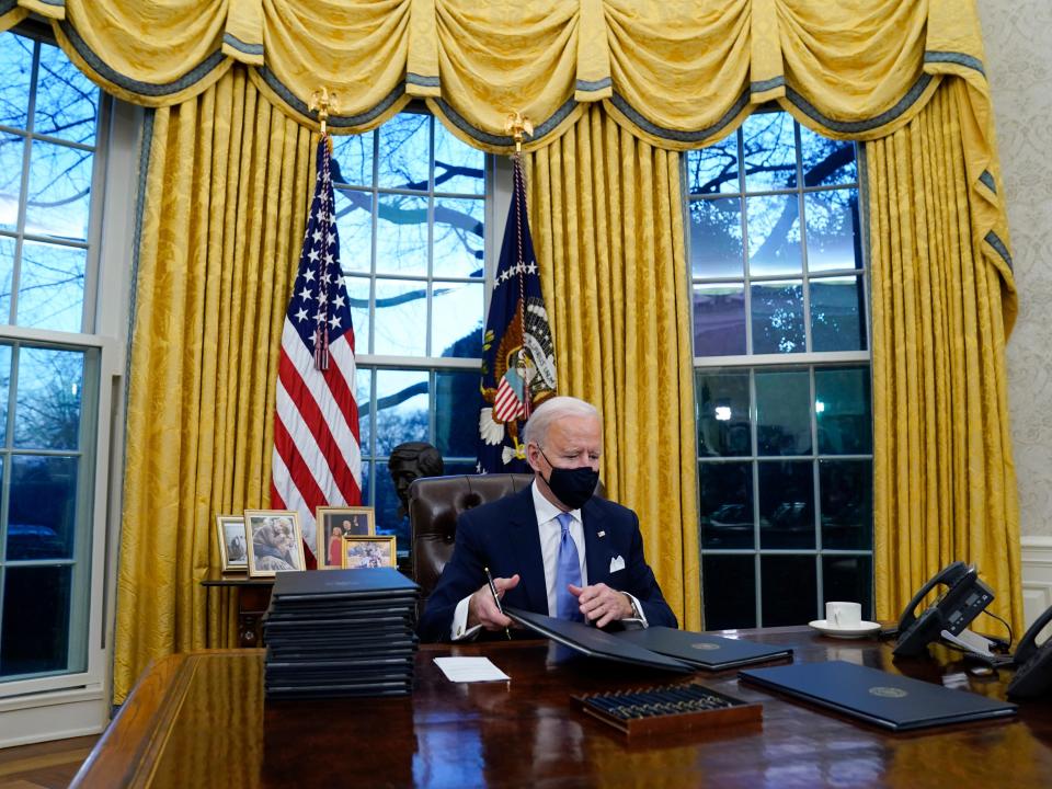 President Joe Biden signs his first executive orders in the Oval Office of the White House on Wednesday, Jan. 20, 2021