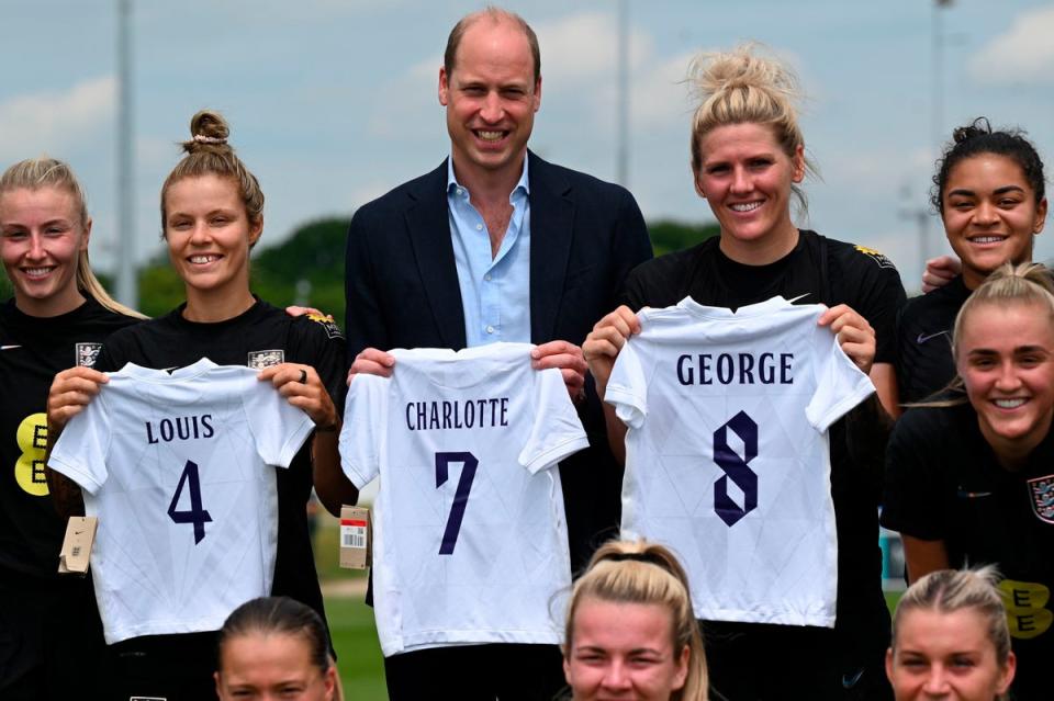 Prince William holding the England football jersey bearing the names of his three children and with the England women football team (AP)
