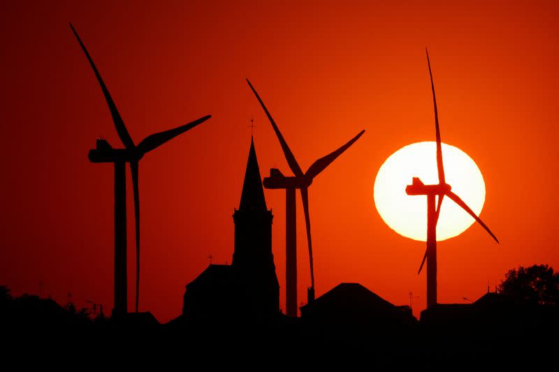 Power-generating windmill turbines and the church of the village are pictured during sunset at a wind park in Bethencourt