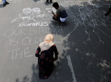 People draw and write messages on a road during a protest against the scrapping of the special constitutional status for Kashmir by the government, in New Delhi