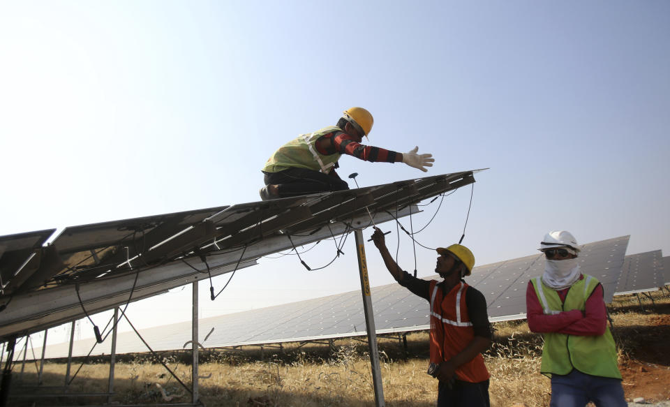 FILE - Workers install solar panels at the Pavagada Solar Park 175 Kilometers north of Bangalore, India, March 1, 2018. Renewable projects have grown steadily in India for years, but a mix of policy decisions, politics and supply chain issues have slowed progress on solar projects in 2023. (AP Photo/Aijaz Rahi, File)