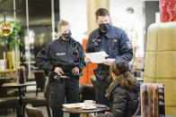 Police officers check the vaccination certificates of guests in a restaurant in Hannover, Germany, Monday, Nov. 29, 2021. On behalf of the local authorities, the police are starting to patrol restaurants and other catering establishments in order to check the measures to battle the spread of the coronavirus. (Ole Spata/dpa via AP)