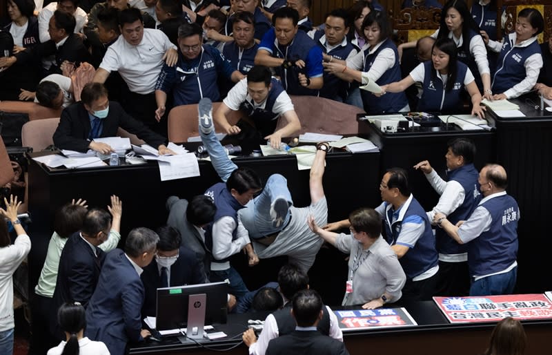 立法院會17日處理藍白所提國會改革相關法案，晚間民進黨立院黨團嘗試占領主席台，民進黨立委邱志偉（灰衣掉落者）嘗試爬過人群占領主席台，雙方爆發衝突，衝突中邱志偉不慎摔落。（中央社）