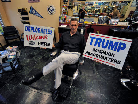 Barber Andrew Ciresi holds Trump campaign signs as he speaks about the current U.S. President in the county which flipped from voting for Barack Obama in 2012 to backing Trump in Pinellas County, Florida, U.S., April 25, 2017. REUTERS/Steve Nesius